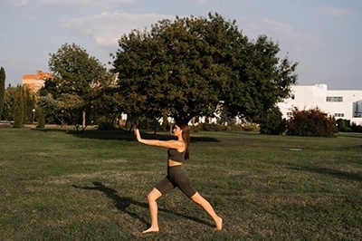 Asiatisk flicka gör tai chi på grönt gräs