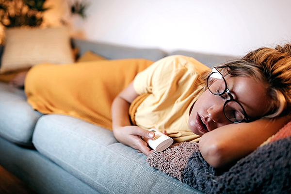 Kvinna som snoozar på soffan med TV på