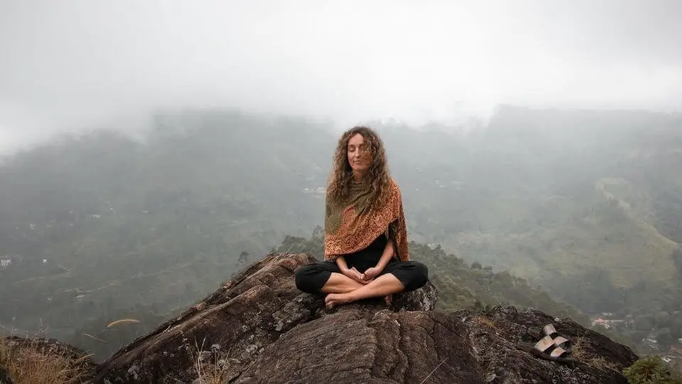 En dam som utövar mindfulness-meditation för avkoppling utomhus i naturen